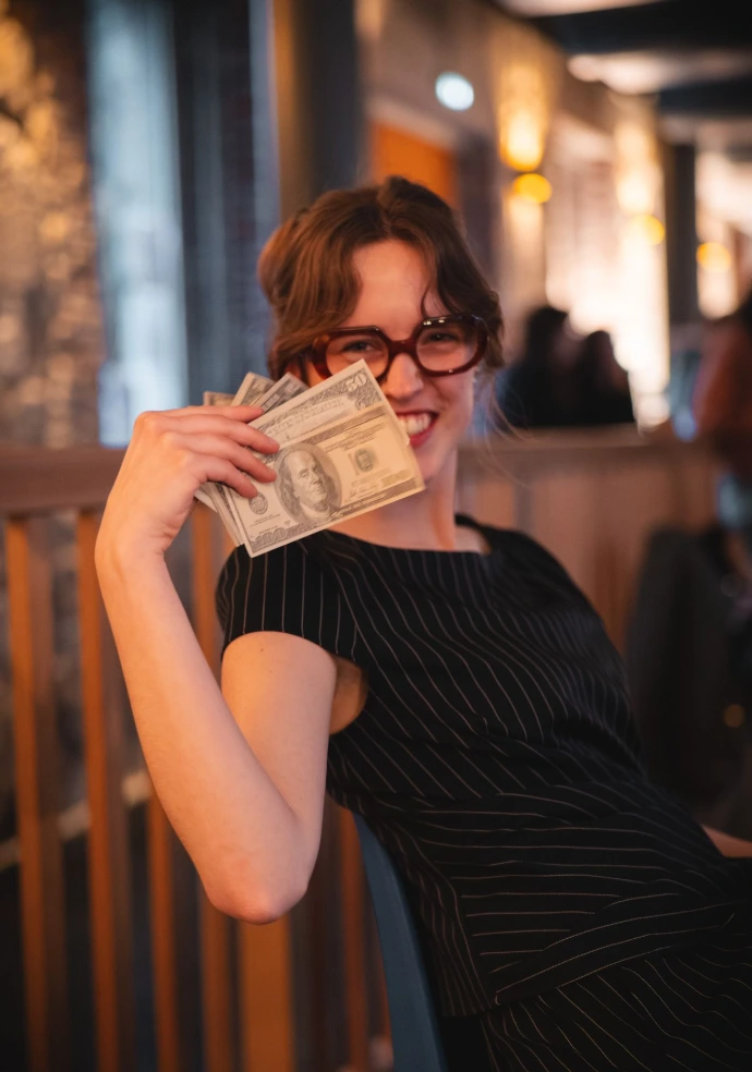 Photo portrait d'une joueuse lors de la soirée, souriante, et agitant des billets factices.