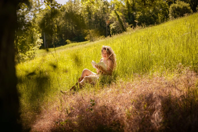 Ana Maria, la modèle durant ce shooting photo, est assise dans un champ de blé. L'arbre au premier plan forme un cadre sur le sujet