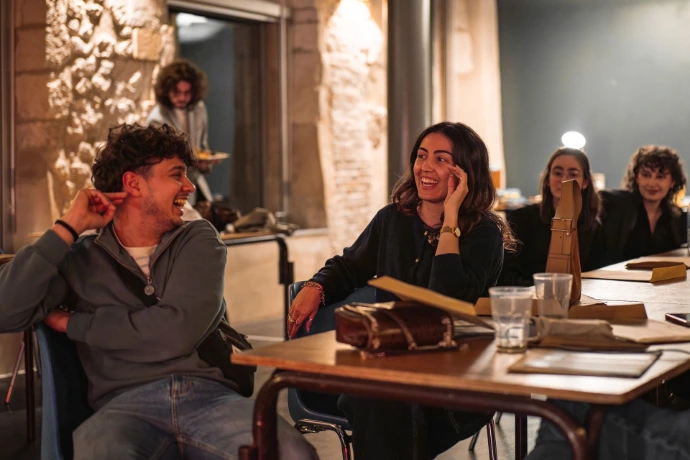 Photo de la fin de soirée, c'est un portrait large d'une femme et d'un homme rigolant grandement lors de l'annonce des vainqueurs. La photo est prise à leurs niveaux, près de la table.