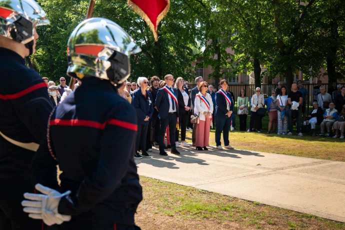 Un pompier de Grand Quevilly au premier plan de dos. Il fait face au maire et son adjoint à quelques mètres devant une foule.