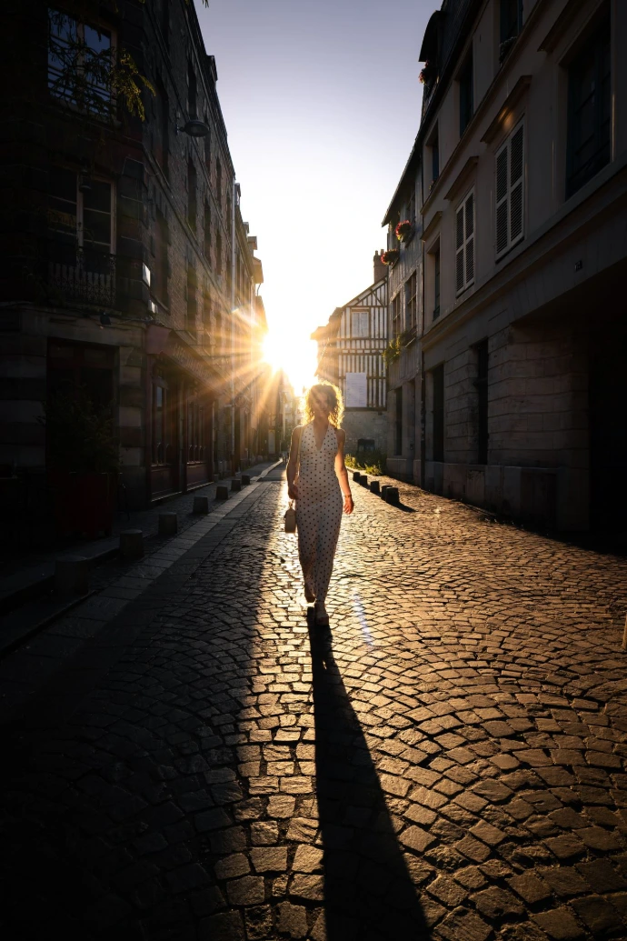 Photo prise pendant le shooting d'Ellia à Rouen. Un plan moyen mettant en contraste la silhouette du modèle dans une rue de Rouen, avec le soleil rouennais en fond.